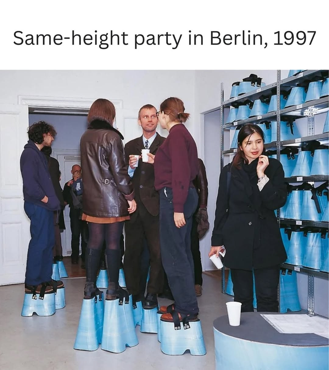Hans Hemmert's 'Level' installation at Gallery Gebauer in Berlin, 1997: partygoers stand on custom blue platform shoes of varying heights so everyone in the room is exactly 2 meters tall.